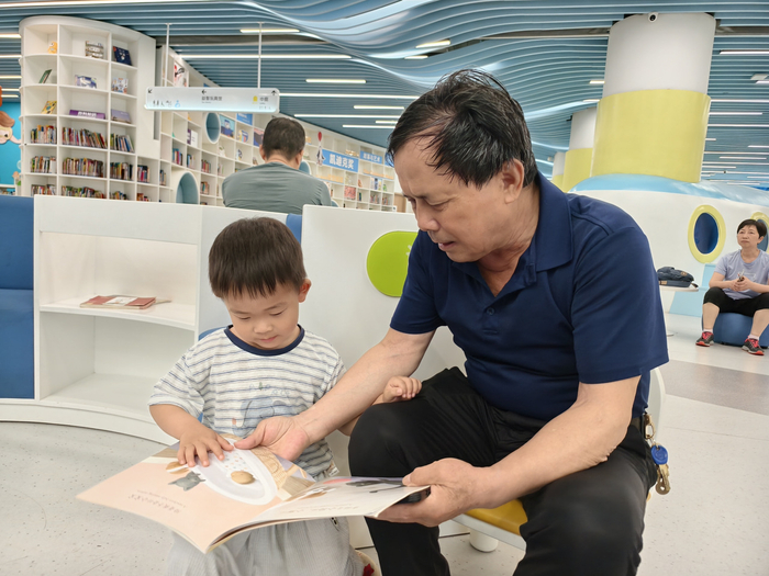 王财发带孙子王栩荞来看书。周晓思摄